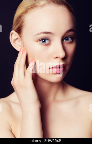 Im Blick der Kameras gefangen. Schönheitsporträt einer jungen blonden Frau vor schwarzem Hintergrund. Stockfoto