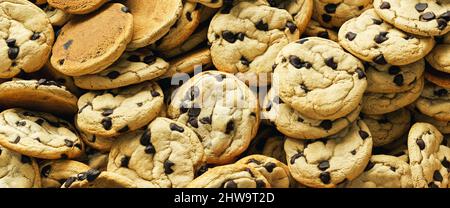 Haufen frisch gebackene Plätzchen mit Schokoladenstückchen als Hintergrundtextur Stockfoto