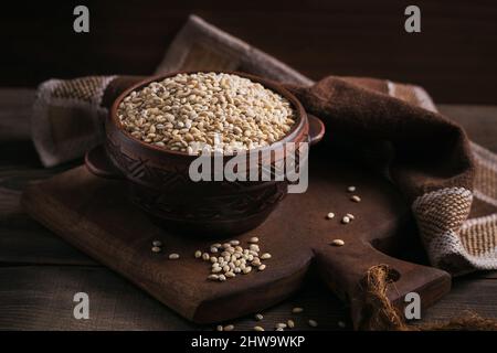 Bio-getrocknete Gerste Getreide in einer Schüssel auf dunklem Holzhintergrund. Gesunde Ernährung und Konzept der Ernährung. Stockfoto