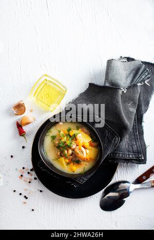 Pea-Suppe mit Speck und Petersilie in einer Schüssel auf weißem Grund. Selektiver Fokus Stockfoto