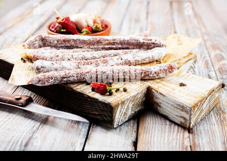 Traditionelle weiße Salami-Wurst, in Scheiben geschnittene Salami isoliert auf weißem Hintergrund. Ganze trockene Salami-Wurststäbchen. Stockfoto