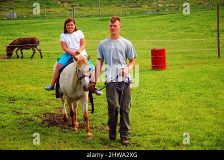 Ein junges Mädchen macht einen Eselritt auf einer Farm Stockfoto