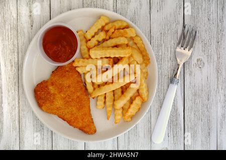 Homestyle Fisch und Chips mit Tomatenketchup im flachen Lay-Format auf rustikal weiß lackierten Brettern. Heiße knusprige goldene Komfornahrung. Stockfoto