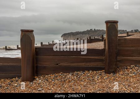 An einem stürmischen Tag blickt man entlang der Küste auf die hölzernen Wellenbrüche an einem Strand in Südbritannien Stockfoto