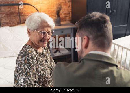 Das Porträt einer eleganten kaukasischen älteren Dame mit Brille und einem Lächeln auf ihren erfolgreichen Sohn mittleren Alters verschwommen den Vordergrund. Hochwertige Fotos Stockfoto
