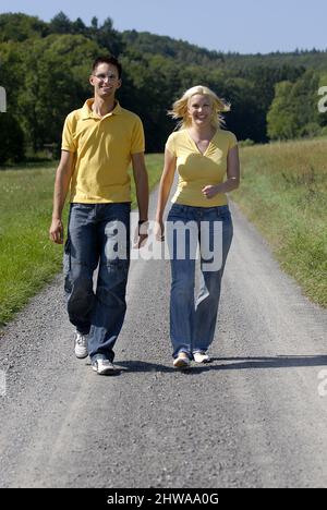 Junges Paar, das auf einer Landstraße läuft, Deutschland Stockfoto