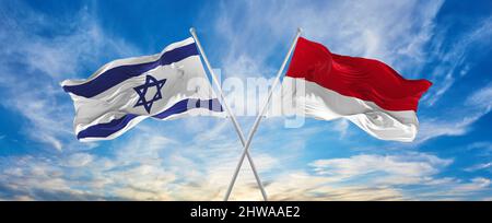 Gekreuzte Nationalflaggen von Israel und Monaco, die im Wind bei bewölktem Himmel winken. Symbolisiert Beziehung, Dialog, Reisen zwischen zwei Ländern. Stockfoto