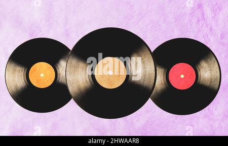 Drei Vinylplatten im Vintage-Stil auf rosa Pelzhintergrund. Stockfoto