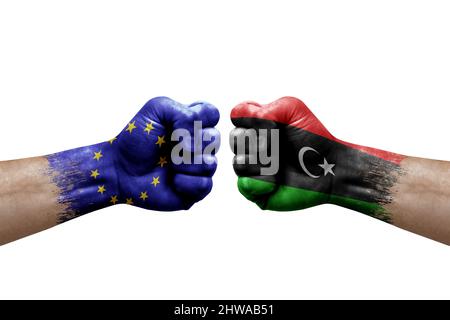 Zwei Hände schlagen sich gegenseitig auf weißem Hintergrund zu. Länderflaggen bemalten Fäuste, Konfliktkrisenkonzept zwischen der europäischen Union und libyen Stockfoto