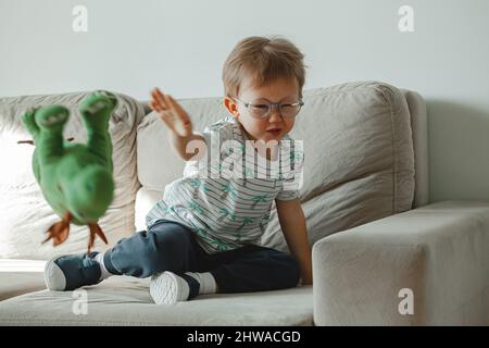 Ein Kind mit Autismus in einer Brille sitzt auf dem Sofa und traurig, wütend Stockfoto