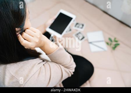 Eine Schwangerschaft und Musik. Bauch der Schwangeren und Kopfhörer im Zimmer Stockfoto