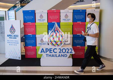 Bangkok, Thailand. 04. März 2022. Ein Mann, der eine Gesichtsmask trägt, als Vorsichtsmaßnahme gegen die Verbreitung von covid-19, geht am APEC 2022 Logo vorbei, das im Siam Paragon, dem Einkaufszentrum, angezeigt wird. Die APEC 2022, oder Asia-Pacific Economic Cooperation 2022, wird im Dezember 2022 in Bangkok, Thailand, stattfinden, wobei noch kein spezifischer Termin festgelegt ist. Das Thema der APEC 2022 lautet „Open, Connect, Balance“. (Foto von Peerapon Boonyakiat/SOPA Images/Sipa USA) Quelle: SIPA USA/Alamy Live News Stockfoto