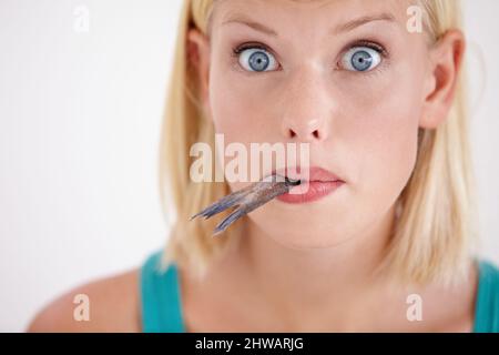 Der Geschmack dieses Fisches ist überraschend. Porträt einer jungen Frau, die einen ganzen Fisch isst. Stockfoto