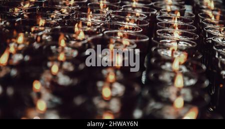 Detail von vielen roten Votivkerzen leuchten im chinesischen Tempel. Reihen von Windlicht-Kerzen im Glas mit geringer Schärfentiefe, verschwommen von Kerzen, Rot ca. Stockfoto