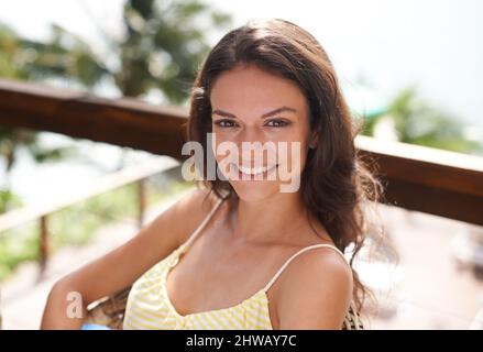 Sonne tanken. Porträt einer jungen Frau, die im Urlaub draußen sitzt und sich entspannt. Stockfoto