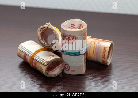 Aufgerollte fünftausendste Banknoten russischer Rubel liegen auf dem Tisch. Stockfoto