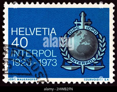 SCHWEIZ - UM 1973: Eine in der Schweiz gedruckte Marke zeigt das Interpol-Emblem, um 1973. Stockfoto