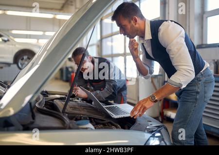 Zwei Techniker, die in der Werkstatt Autodiagnosen durchführen Stockfoto