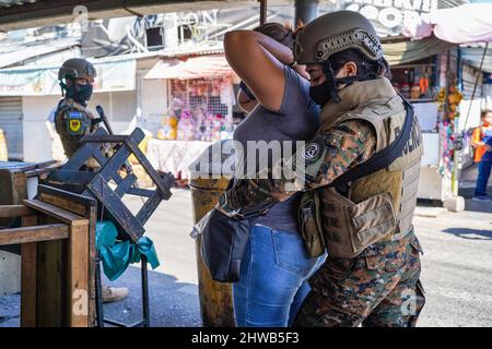 San Salvador, El Salvador. 04. März 2022. Während einer Militärpatrouille in der Innenstadt von San Salvador sucht eine Soldatin eine Frau auf einem Straßenmarkt. Seit 2000 dürfen Frauen die Reihen der salvadorianischen Streitkräfte integrieren, am 8.. März wird der Internationale Frauentag gefeiert, wobei die Öffnung traditioneller, von Männern geführte Räume für Frauen eine von vielen Forderungen ist. Kredit: SOPA Images Limited/Alamy Live Nachrichten Stockfoto