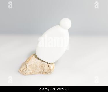 Kosmetisches Modell. Spa Relax Komposition mit weißer Kosmetikflasche auf einem steinernen Podium auf einem weißen Tisch mit Kopierfläche. Mock up für natürliche Bio-Bea Stockfoto