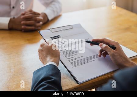 Nahaufnahme Hand halten Lebenslauf und r Interview Kandidat für eine Stelle im Besprechungsraum im Büro zu bewerben. Stockfoto