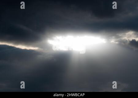 Sonnenstrahlen durchbrechen die Lücke in dunklen Wolken - Wetterwechsel mit dynamischen Wolken Stockfoto