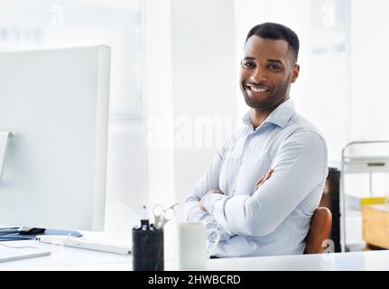 HES zuversichtlich in seine Karriere. Ein hübscher junger afroamerikanischer Geschäftsmann, der an seinem Schreibtisch arbeitet. Stockfoto