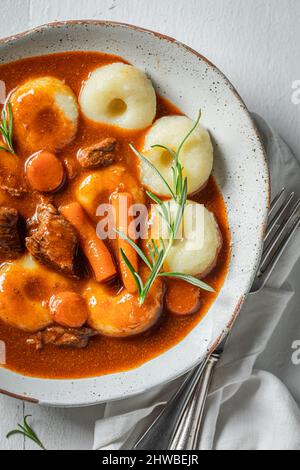 Schlesische Nudeln mit Gulasch aus Rindfleisch und Gemüse auf weißem Teller Stockfoto