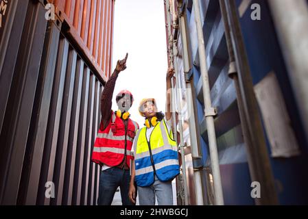 Zwei afroamerikanische Arbeiter kontrollieren und kontrollieren die Verladung von Frachtschiffen vom Frachtschiff für den Import-Export. Stockfoto