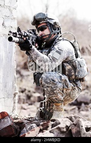 Führen des Assults. Ein Soldat hockte sich neben einer abgebrochenen Wand und zeigte seine Waffe in die Ferne. Stockfoto