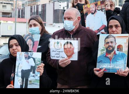 Beirut, Libanon. 04. März 2022. Familien von Opfern der Explosion versammeln sich vor der Auswandererstatue vor dem Hafen, um den 19.. Monat der Explosion zu markieren, Beirut, Libanon, März 4 2022. Die Familien protestieren gegen Beamte, die die Ermittlungen im Zusammenhang mit Hafensprengen behindern, die von Richter Tareq Bitar geleitet werden. Sie prangern auch den Willen der Regierung an, die verwüsteten Getreidesilos abzureißen, das heißt, mit ihren Worten, "die Erinnerung zu töten" an die Katastrophe. Die Demonstranten zeigen Portraits ihrer Lieben und halten ein Transparent mit der Aufforderung zur „Beseitigung von Hindernissen für die Ermittlungen und zur raschen Verhaftung von Kriminellen“. Stockfoto