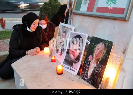 Beirut, Libanon. 04. März 2022. Familien von Opfern der Explosion versammeln sich vor der Auswandererstatue vor dem Hafen, um den 19.. Monat der Explosion zu markieren, Beirut, Libanon, März 4 2022. Die Familien protestieren gegen Beamte, die die Ermittlungen im Zusammenhang mit Hafensprengen behindern, die von Richter Tareq Bitar geleitet werden. Sie prangern auch den Willen der Regierung an, die verwüsteten Getreidesilos abzureißen, das heißt, mit ihren Worten, "die Erinnerung zu töten" an die Katastrophe. Die Demonstranten zeigen Portraits ihrer Lieben und halten ein Transparent mit der Aufforderung zur „Beseitigung von Hindernissen für die Ermittlungen und zur raschen Verhaftung von Kriminellen“. Stockfoto