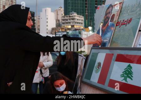 Beirut, Libanon. 04. März 2022. Familien von Opfern der Explosion versammeln sich vor der Auswandererstatue vor dem Hafen, um den 19.. Monat der Explosion zu markieren, Beirut, Libanon, März 4 2022. Die Familien protestieren gegen Beamte, die die Ermittlungen im Zusammenhang mit Hafensprengen behindern, die von Richter Tareq Bitar geleitet werden. Sie prangern auch den Willen der Regierung an, die verwüsteten Getreidesilos abzureißen, das heißt, mit ihren Worten, "die Erinnerung zu töten" an die Katastrophe. Die Demonstranten zeigen Portraits ihrer Lieben und halten ein Transparent mit der Aufforderung zur „Beseitigung von Hindernissen für die Ermittlungen und zur raschen Verhaftung von Kriminellen“. Stockfoto