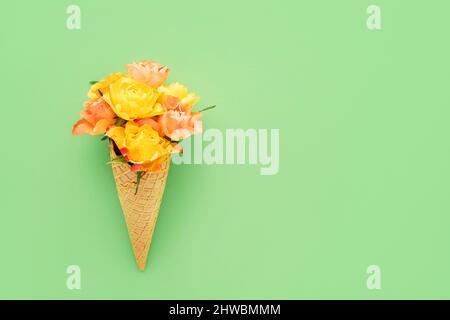 Gelbe Rosen in einem Waffel-Eis-Kegel auf grünem Hintergrund. Muttertag, Valentinstag, Bachelorette, Sommerkonzept. Platz kopieren, Draufsicht Stockfoto