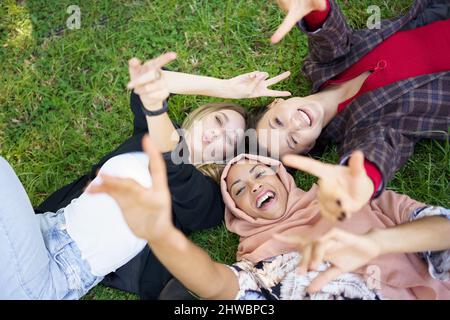 Glückliche, vielfältige Frauen liegen auf dem Rasen Stockfoto