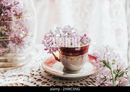 Retro-Teetasse mit Fliederblüten darin. Heimtextilien. Frühlingsstimmung Stockfoto