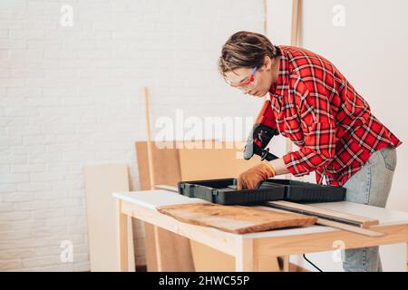 Das Mädchen der Arbeiterin nimmt den Bohrer für den Bohrer heraus Stockfoto