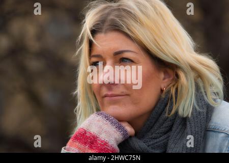 Porträt einer blonden Frau mit blauen Augen, die wegschaut Stockfoto