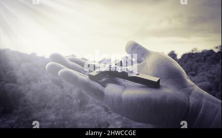 Hand hält das Heilige Kreuz mit hell leuchtendem Licht. Stockfoto