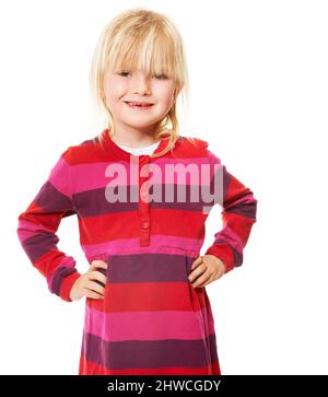 Shes das süßeste kleine Mädchen. Ein nettes kleines blondes Mädchen lächelt, während sie mit ihren Händen auf ihren Hüften steht. Stockfoto