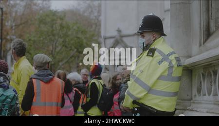 London, Großbritannien - 11 20 2021: Ein diensthabende Polizeibeamter, der eine Gesichtsmaske trägt, vor den Royal Courts of Justice on Strand, für einen beleidigenden britischen Protest. Stockfoto