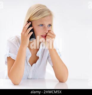 Das kann nicht wahr sein. Aufnahme einer attraktiven Frau, die beim Telefonieren besorgt aussieht. Stockfoto