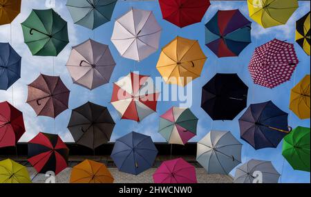 Bunte Regenschirme, die an einer Straße hängen - von unten nach oben Stockfoto