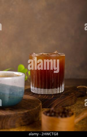 Ein aromatischer Kaffee, der frisch zum Ausgießen gemahlen wird, wird auf einem rustikalen Holztablett zu heißem oder kaltem schwarzen Kaffee Stockfoto