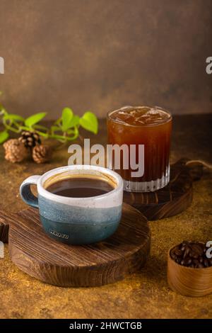 Ein aromatischer Kaffee, der frisch zum Ausgießen gemahlen wird, wird auf einem rustikalen Holztablett zu heißem oder kaltem schwarzen Kaffee Stockfoto