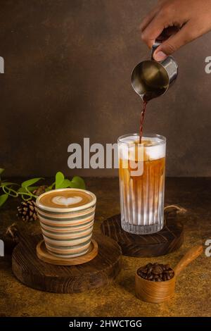Ein aromatischer Kaffee, der frisch zum Ausgießen gemahlen wird, wird auf einem rustikalen Holztablett zu heißem oder kaltem schwarzen Kaffee Stockfoto
