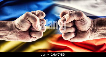 Konfrontation zweier Fäuste über den Flaggen der Ukraine und Russlands. Stockfoto