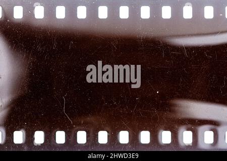 Staubige und schmutzige 35-mm-Filmtextur oder -Oberfläche. Perforierter, zerkratzter Kamerafilm isoliert auf weißem Hintergrund. Stockfoto