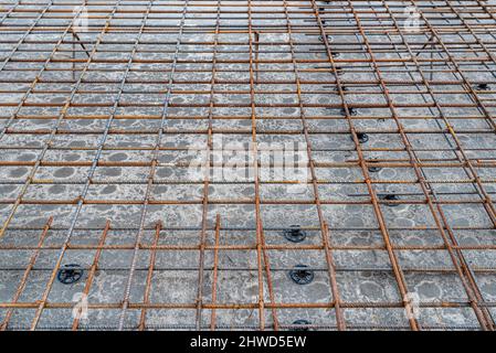 Die Fundamentplatte besteht aus Verstärkungsstäben, gebunden mit Zugdraht, verklebte Verstärkung aus der Nähe sichtbar. Stockfoto