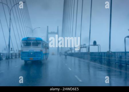 Verschwommenes Bild von Howrah, Westbengalen, Indien. Aufnahme durch Regentropfen, die auf die Windschutzscheibe des Autos fallen, nasses Glas, Verkehr an der Hoogly-Brücke 2.. Stockfoto